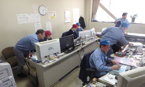 デスクで研究をする作業服のスタッフ達